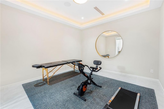 workout room featuring a tray ceiling and baseboards