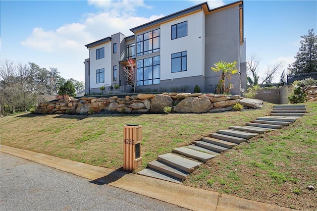contemporary house with stucco siding and a front lawn
