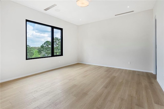 empty room with light wood-type flooring, baseboards, and visible vents