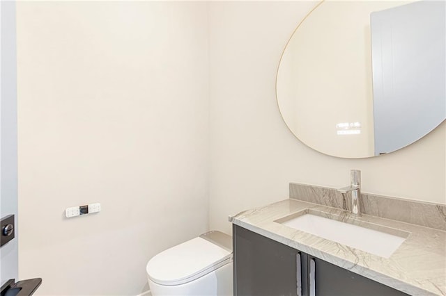 half bath featuring vanity and toilet