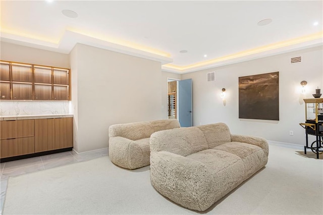 living area featuring a tray ceiling, baseboards, light colored carpet, and visible vents