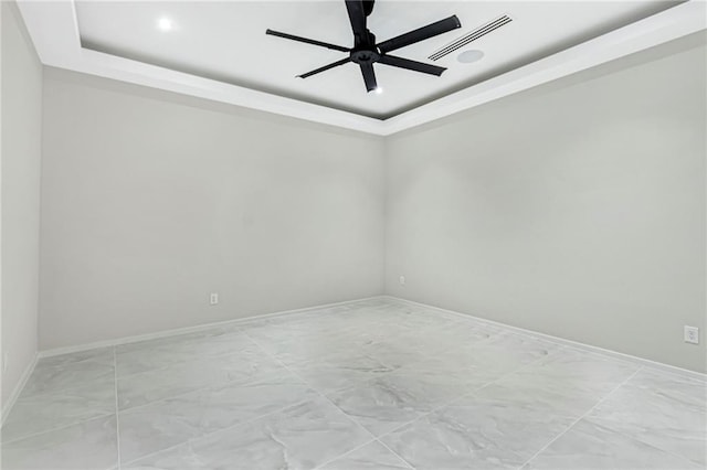 unfurnished room with a raised ceiling, ceiling fan, baseboards, and visible vents