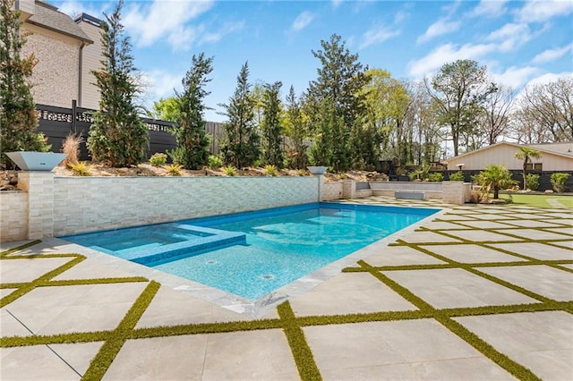 view of swimming pool featuring a patio area, a pool with connected hot tub, and fence
