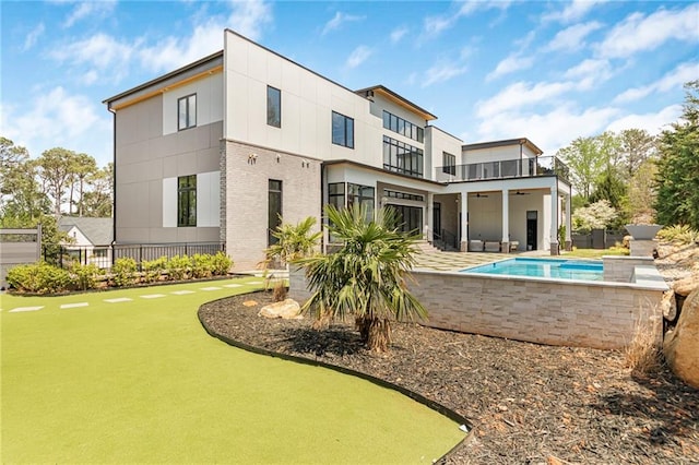 rear view of house with brick siding, a patio area, a fenced in pool, and a balcony