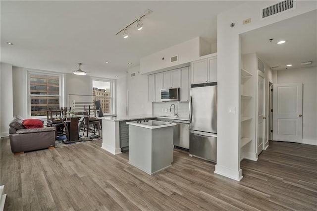 57 Forsyth St NW Unit 14B, Atlanta, GA 30303 - kitchen with stainless steel appliances, a center island, wood finished floors, light countertops, and a sink