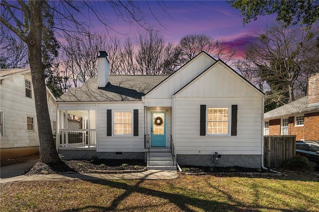 bungalow featuring a chimney, roof with shingles, crawl space, covered porch, and a yard