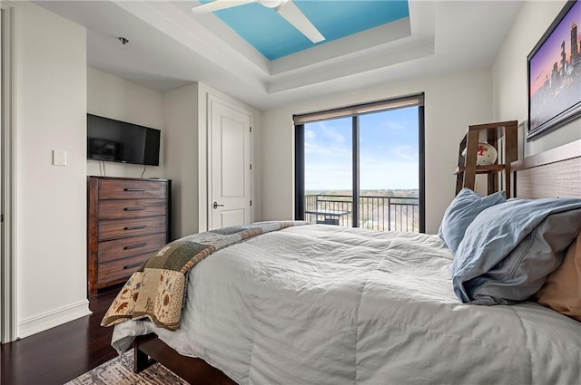 bedroom featuring ceiling fan, baseboards, dark wood finished floors, a raised ceiling, and access to outside