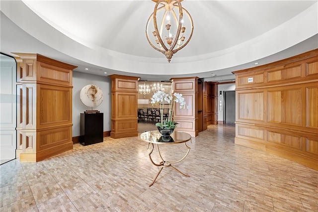 interior space with a tray ceiling, decorative columns, recessed lighting, and a chandelier