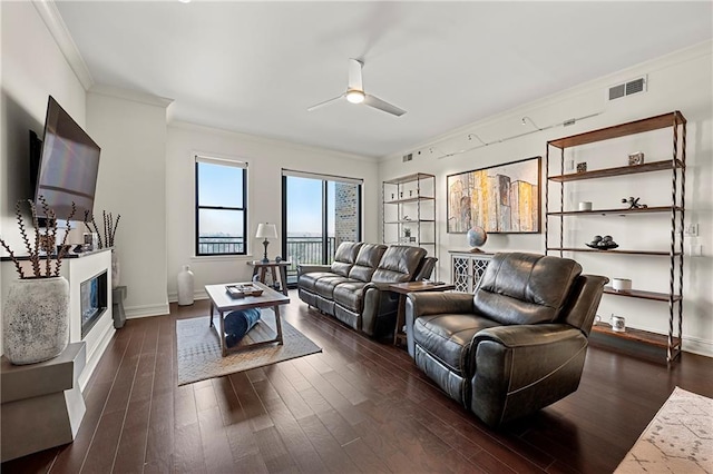 living area with baseboards, visible vents, dark wood finished floors, ornamental molding, and ceiling fan