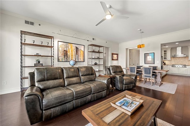 living area with visible vents, wood-type flooring, ceiling fan, and ornamental molding