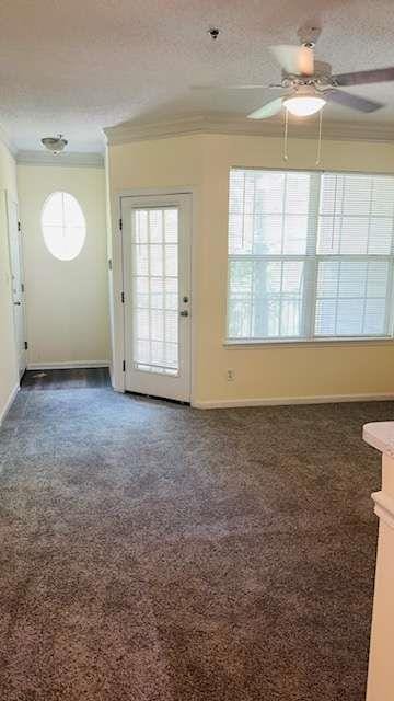 carpeted empty room with ornamental molding, ceiling fan, and a textured ceiling