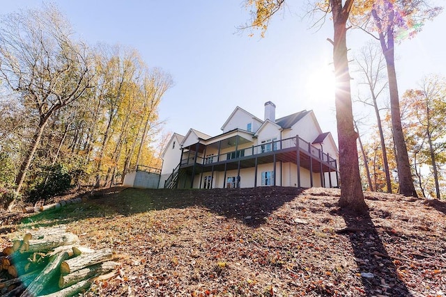 back of property featuring stairway, a chimney, and a wooden deck