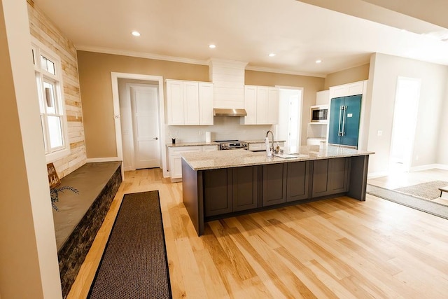 kitchen with a spacious island, white cabinetry, light wood-style floors, appliances with stainless steel finishes, and crown molding