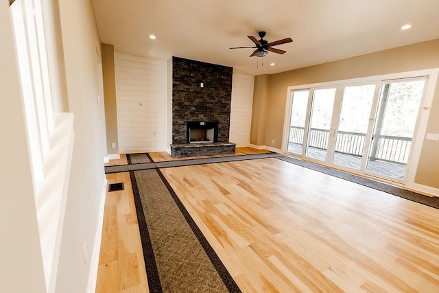 unfurnished living room with a stone fireplace, recessed lighting, a ceiling fan, and wood finished floors