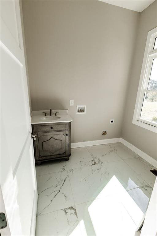 clothes washing area with electric dryer hookup, marble finish floor, washer hookup, a sink, and baseboards