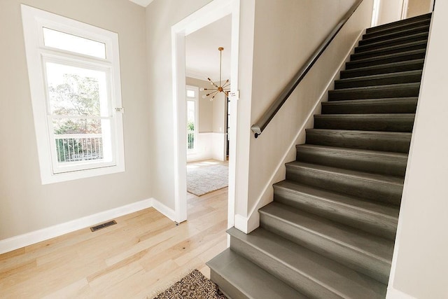 interior space with visible vents, baseboards, stairs, an inviting chandelier, and wood finished floors