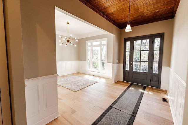 foyer featuring visible vents, wood ceiling, and a wainscoted wall