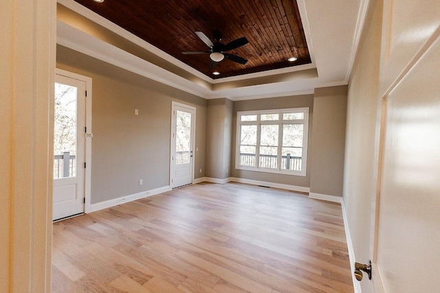 empty room featuring wood ceiling, a tray ceiling, light wood-type flooring, and a healthy amount of sunlight