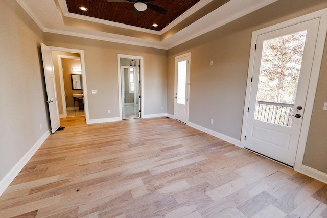 entryway with a tray ceiling, baseboards, light wood-style floors, and crown molding