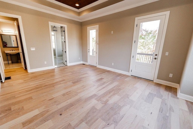 entrance foyer featuring a raised ceiling, light wood-type flooring, baseboards, and ornamental molding