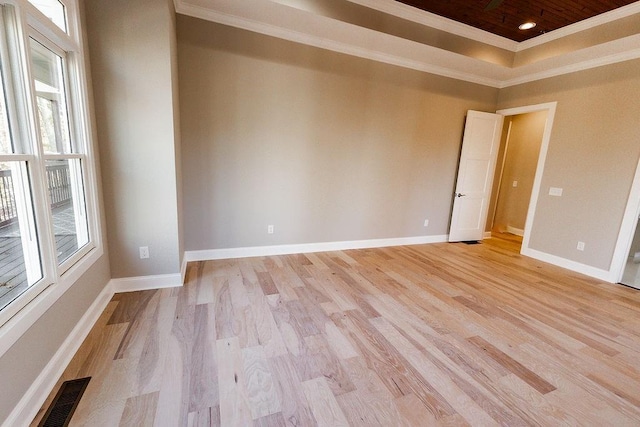 unfurnished room featuring visible vents, baseboards, ornamental molding, light wood-style floors, and a raised ceiling