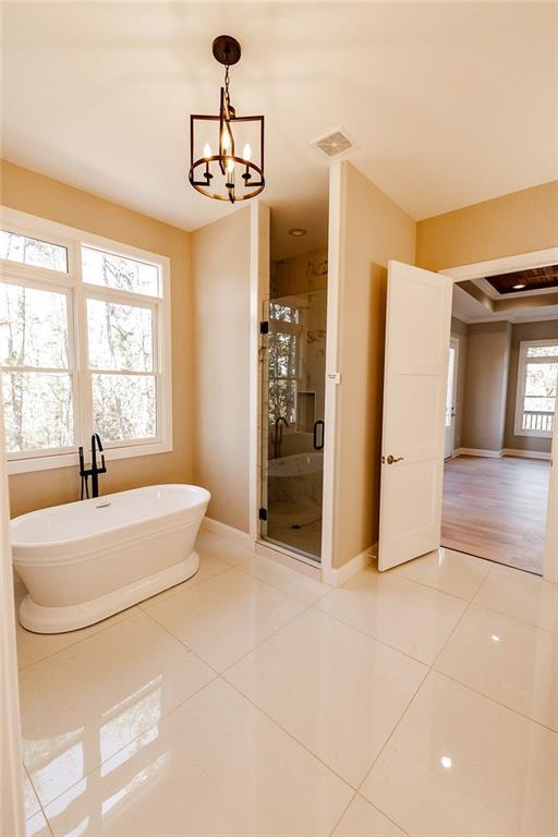 full bath featuring visible vents, a chandelier, a freestanding bath, a stall shower, and tile patterned floors