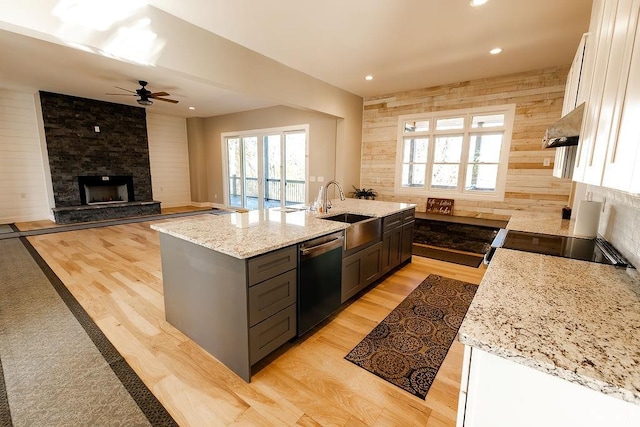 kitchen featuring dishwasher, extractor fan, wood walls, and a sink