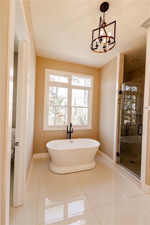 full bath with tile patterned floors, a freestanding tub, visible vents, and a stall shower