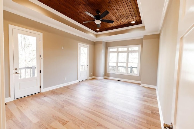 empty room featuring baseboards, light wood-style flooring, crown molding, wood ceiling, and a raised ceiling