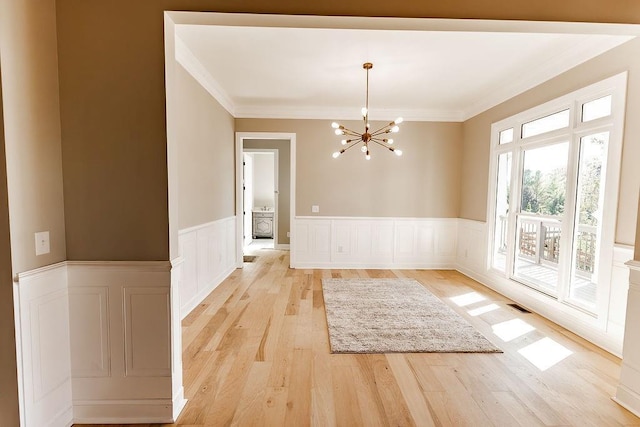 unfurnished dining area with visible vents, a chandelier, crown molding, and light wood finished floors