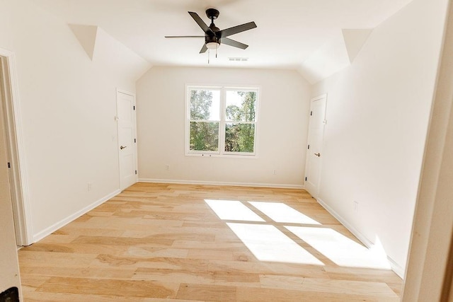 unfurnished room with visible vents, lofted ceiling, a ceiling fan, light wood finished floors, and baseboards