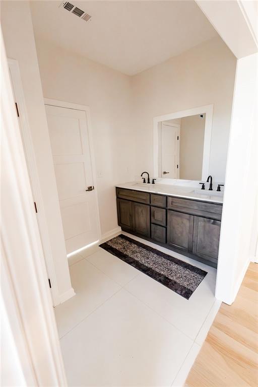 full bathroom with double vanity, baseboards, visible vents, and a sink