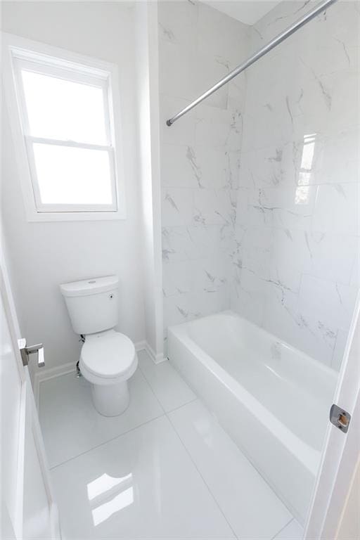 bathroom featuring bathing tub / shower combination, toilet, and baseboards