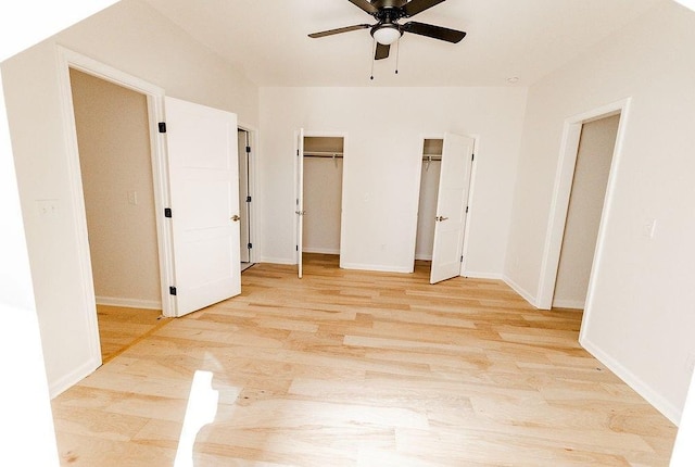 interior space with ceiling fan, light wood-style floors, multiple closets, and baseboards