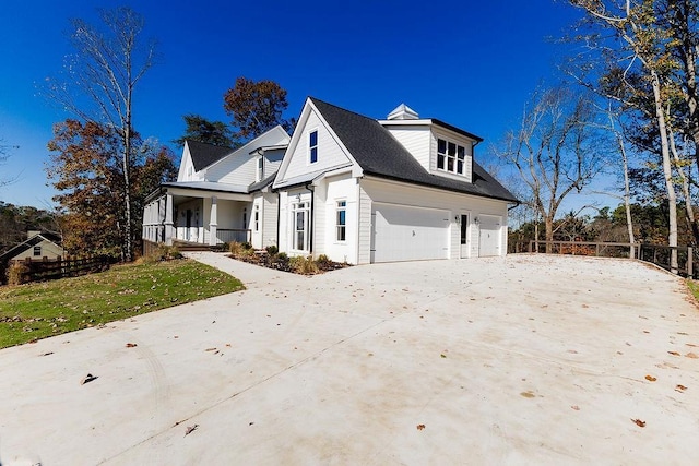 view of front of house with fence, driveway, covered porch, a front lawn, and a garage