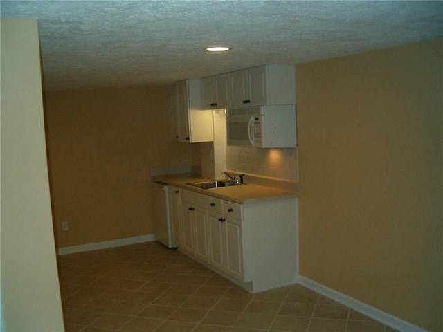 kitchen featuring decorative backsplash, white appliances, sink, light tile patterned floors, and white cabinetry