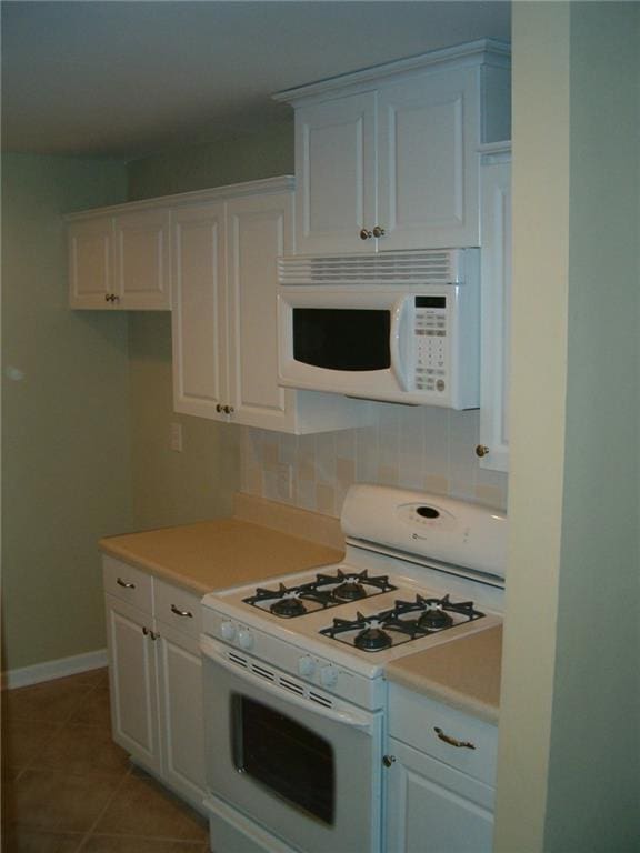 kitchen featuring tasteful backsplash, light tile patterned floors, white cabinets, and white appliances