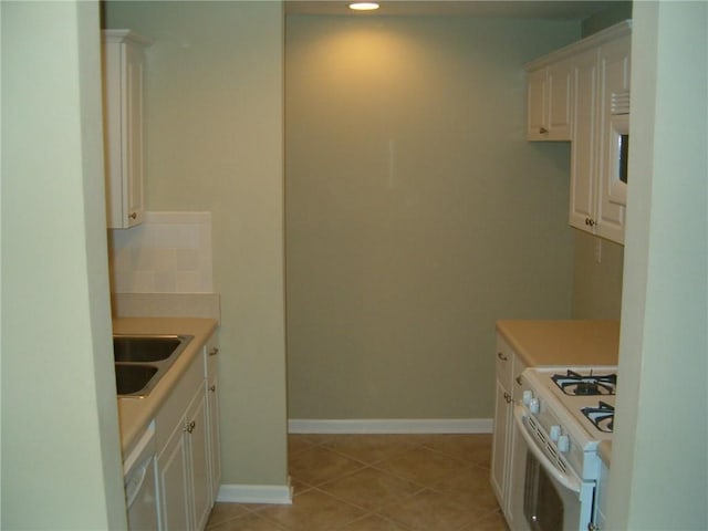 kitchen with light tile patterned flooring, sink, white cabinets, and white range with gas stovetop