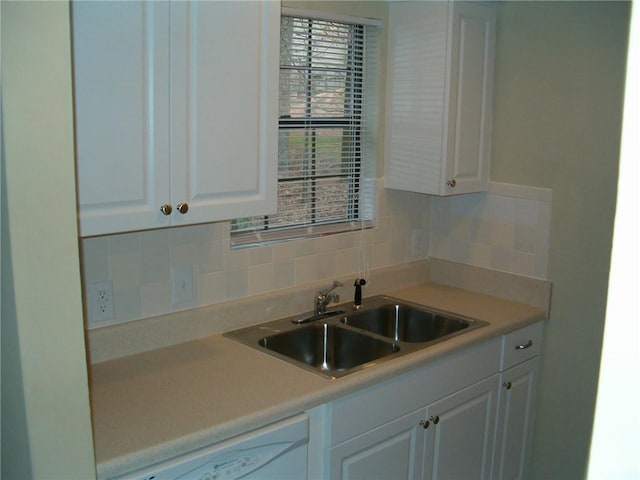 kitchen featuring white cabinets, decorative backsplash, white dishwasher, and sink