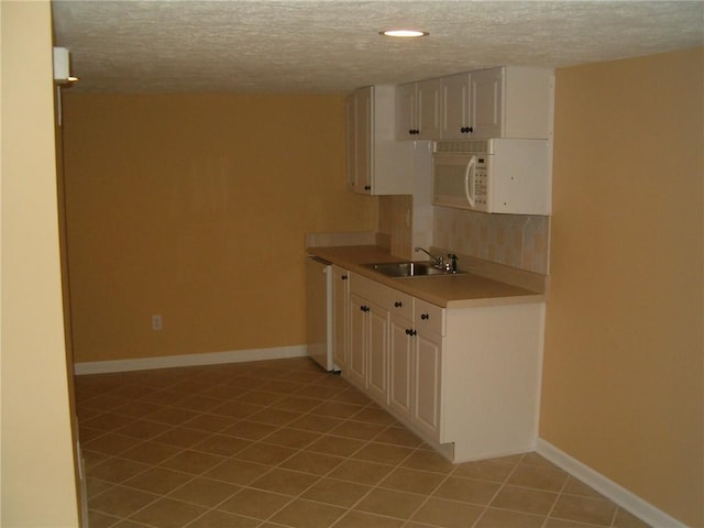 kitchen featuring a textured ceiling, white cabinets, white appliances, and sink