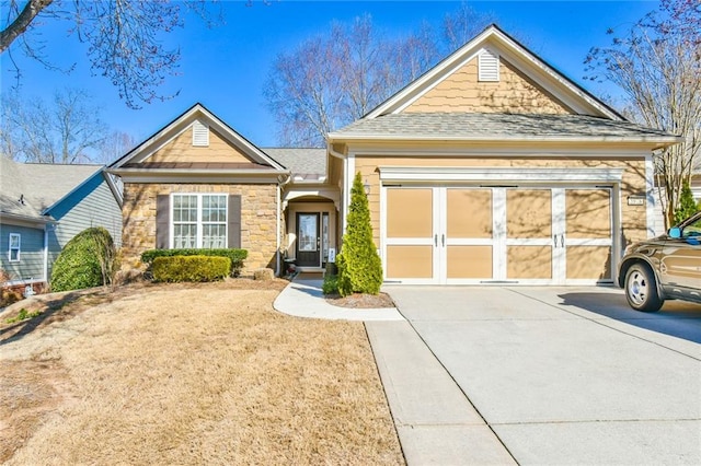 view of front of house featuring concrete driveway, stone siding, an attached garage, and a shingled roof