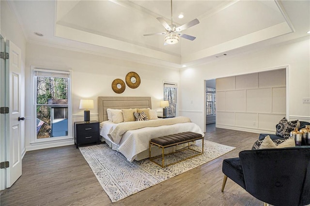 bedroom featuring ceiling fan, ornamental molding, a tray ceiling, and dark hardwood / wood-style flooring