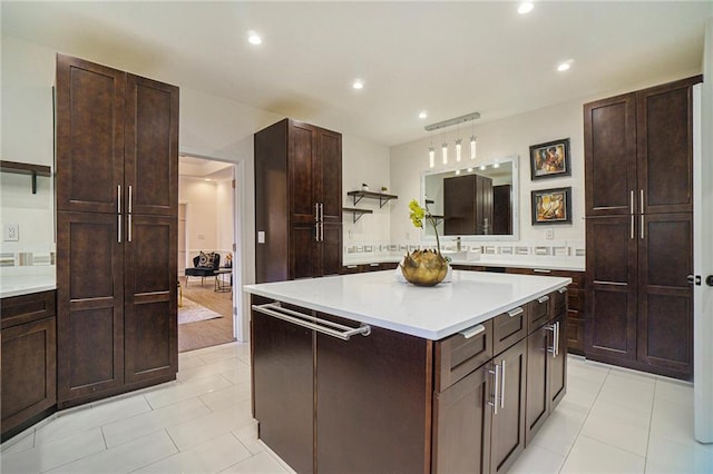 kitchen featuring a kitchen island, dark brown cabinets, light tile patterned floors, and decorative light fixtures