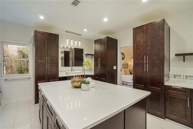 kitchen featuring pendant lighting, sink, a center island, and light tile patterned flooring