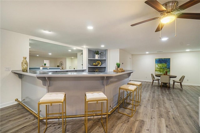 kitchen with a kitchen bar, kitchen peninsula, ceiling fan, hardwood / wood-style floors, and white cabinets