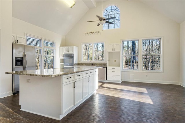 kitchen with stainless steel appliances, dark hardwood / wood-style floors, a center island, light stone countertops, and white cabinets