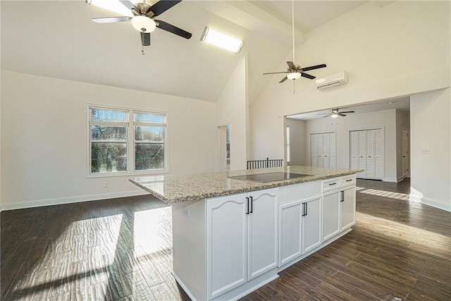 kitchen with dark hardwood / wood-style floors, light stone countertops, white cabinets, a kitchen island, and black electric cooktop