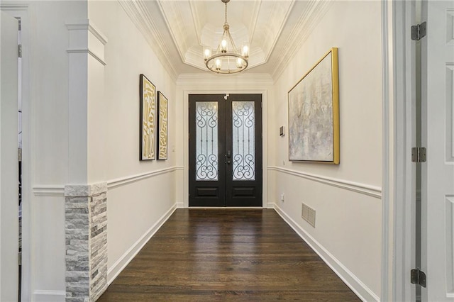 entryway with dark wood-type flooring, an inviting chandelier, a tray ceiling, ornamental molding, and french doors