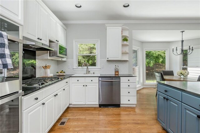 kitchen with blue cabinetry, open shelves, a sink, stainless steel appliances, and white cabinetry