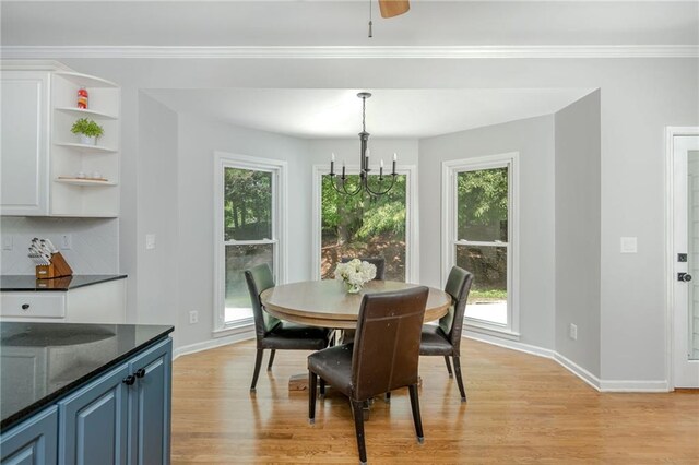 dining space featuring baseboards, an inviting chandelier, ornamental molding, and light wood-style floors